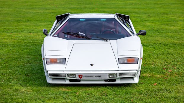 White Lamborghini Countach displayed outdoors on a vibrant green lawn capturing classic automotive elegance.