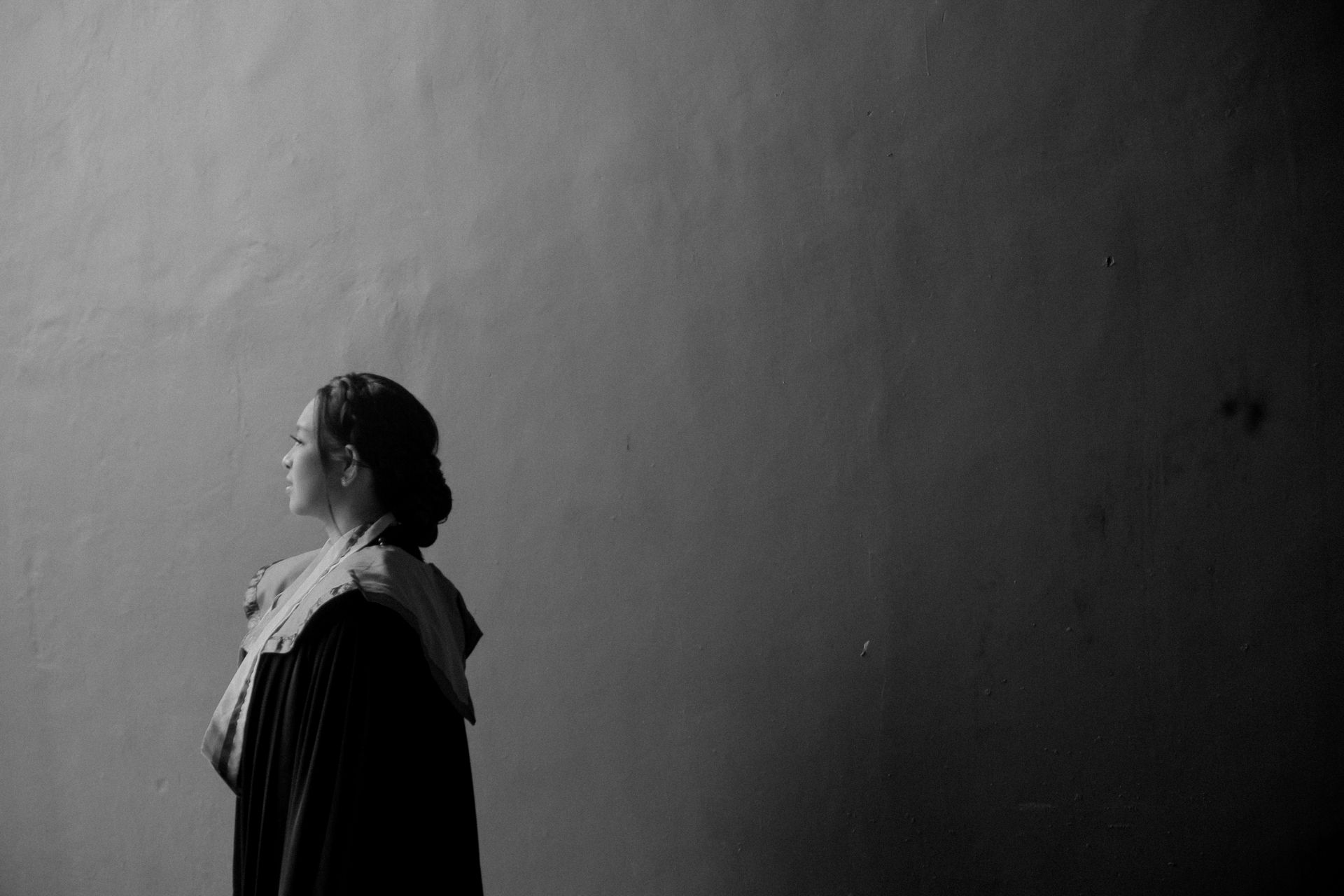 Graceful black and white profile portrait of a graduate indoors.