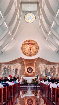 A beautiful church interior featuring a crucifix, stained glass, and worshippers during a service.