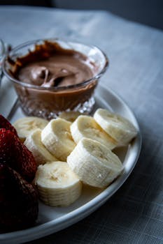 A gourmet dessert plate featuring bananas, strawberries, and chocolate dip.
