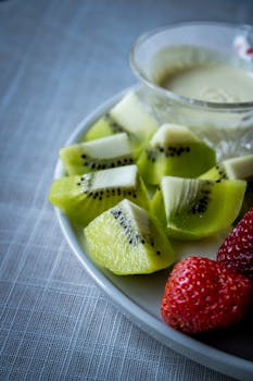 Sliced kiwi and strawberries with cream fondue, a delicious fresh dessert option.