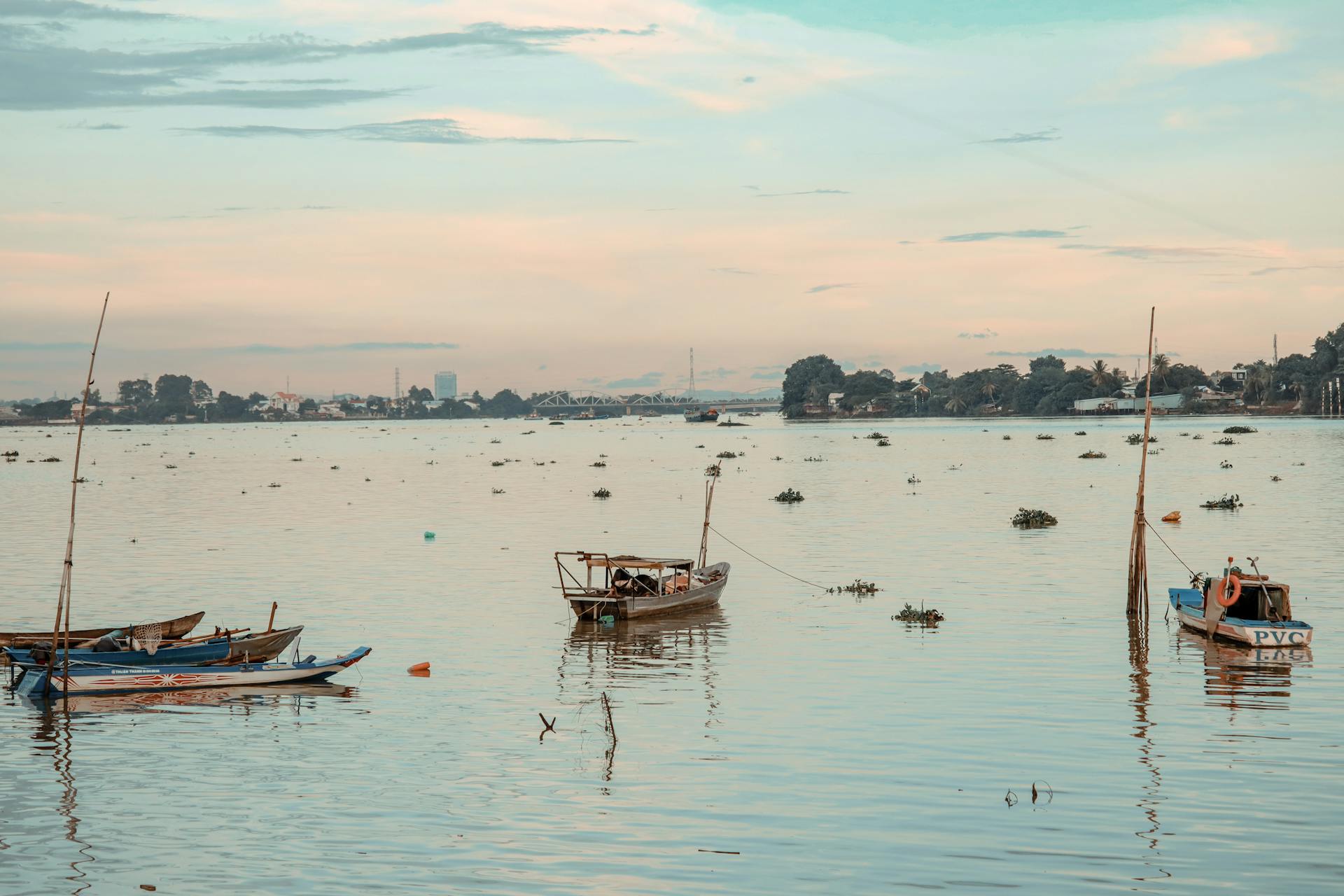 Tranquil scene of boats floating on a lake during sunset, reflecting peaceful evening vibes.