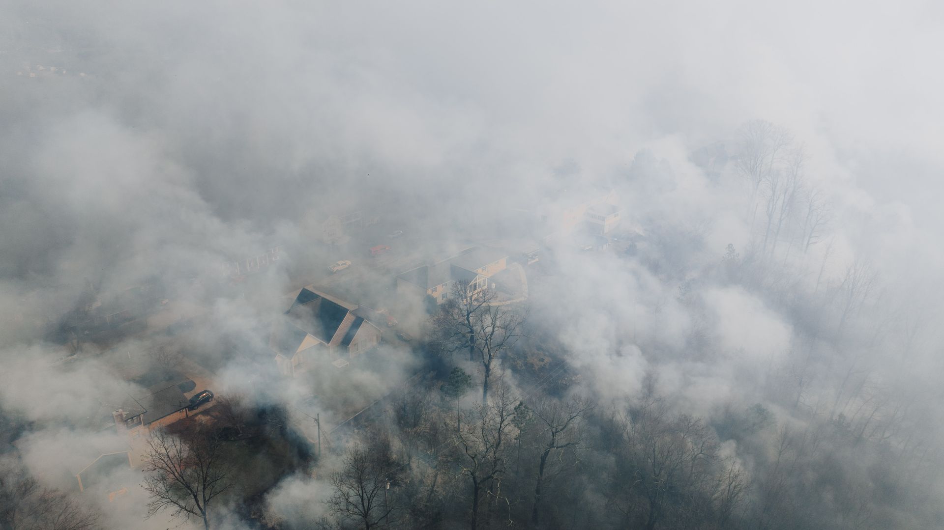 A smoke-covered landscape under a grey, overcast sky