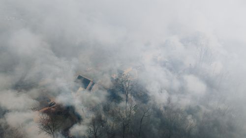 Free Aerial shot of a neighborhood shrouded in smoke, obscuring houses and trees. Stock Photo