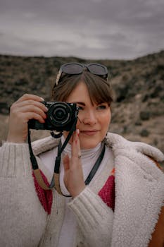 Outdoor portrait of a woman holding a camera in the Albuquerque desert, showcasing fashion and nature.