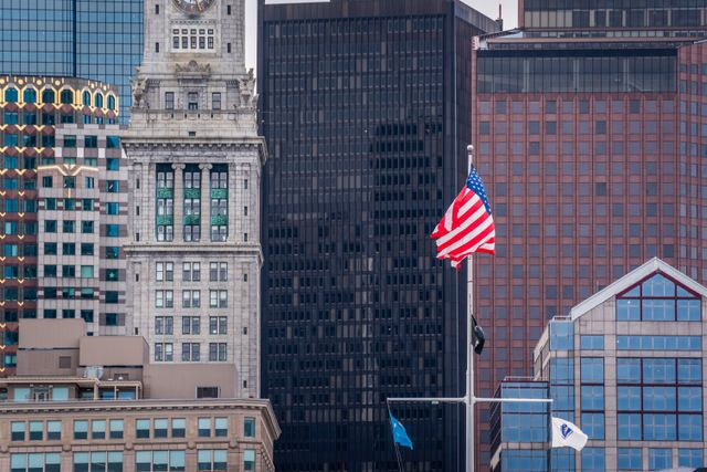 Boston skyline with American flag, representing the US tax claim that follows US citizens to the UK regardless of treaty residence