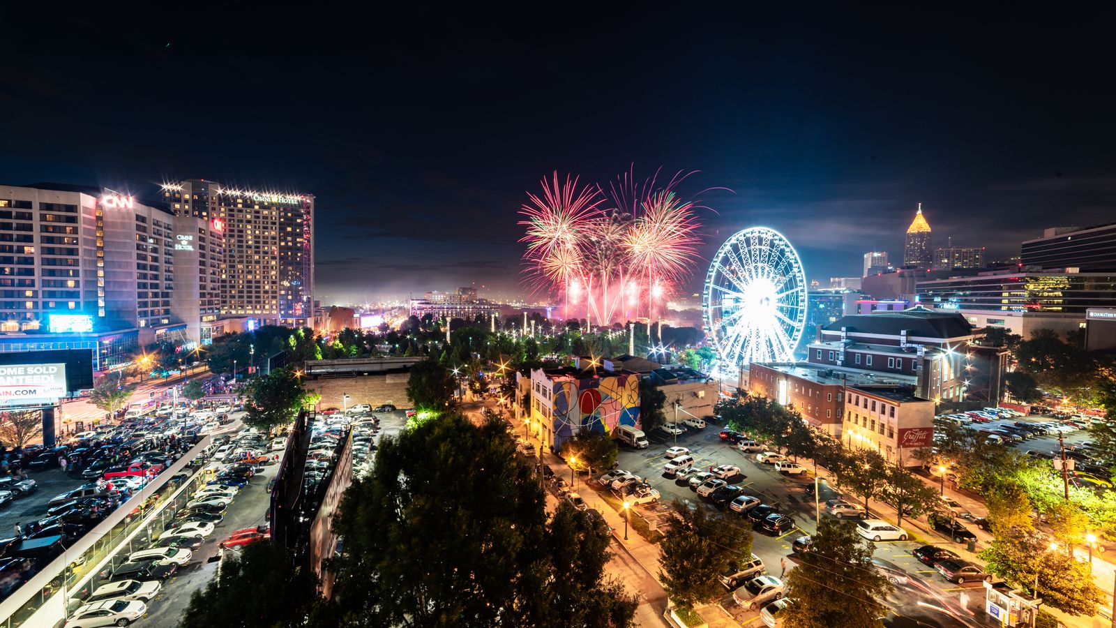 A vibrant display of fireworks illuminates the Atlanta skyline, featuring notable landmarks.