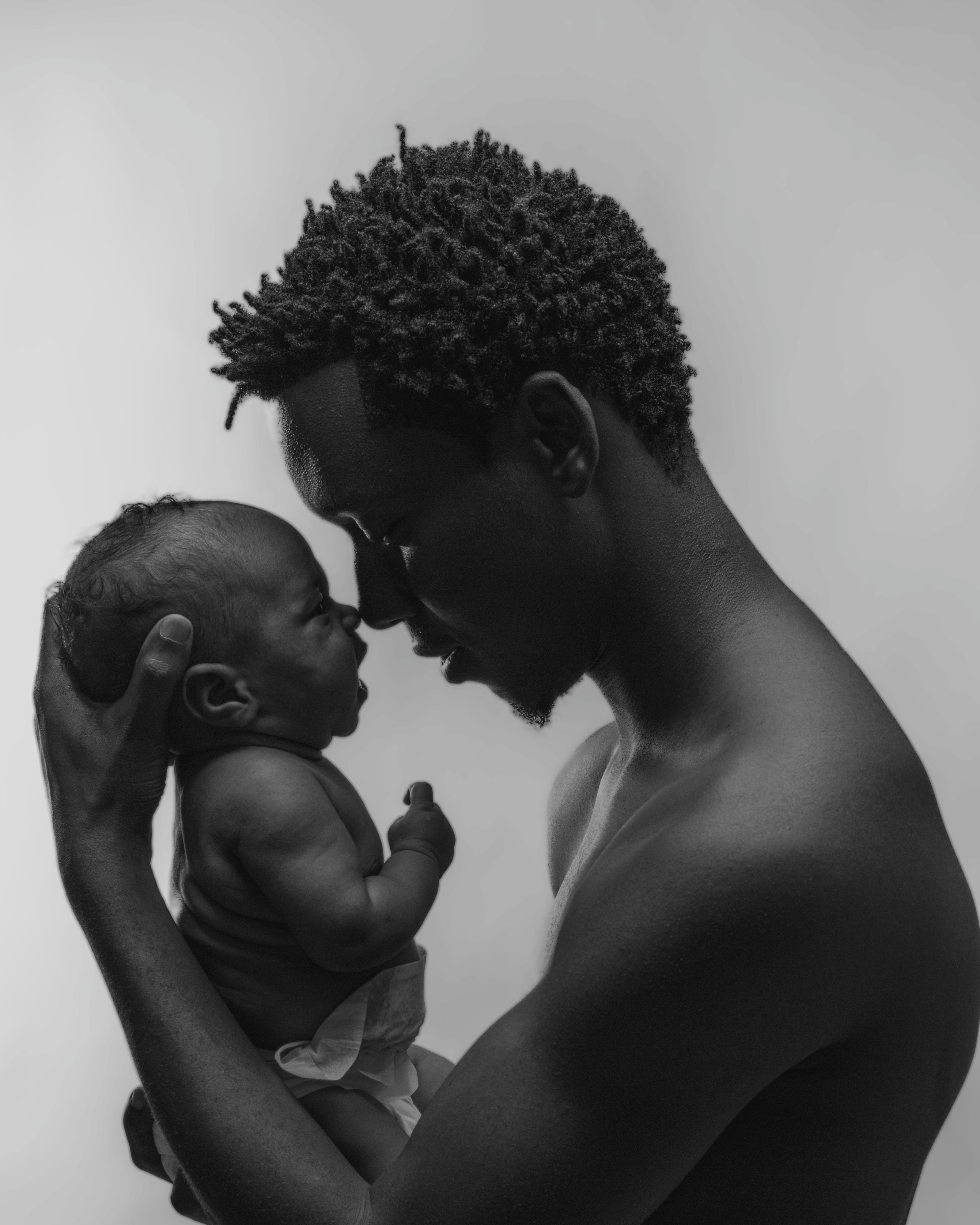 Intimate black and white portrait of an adult and baby bonding closely.