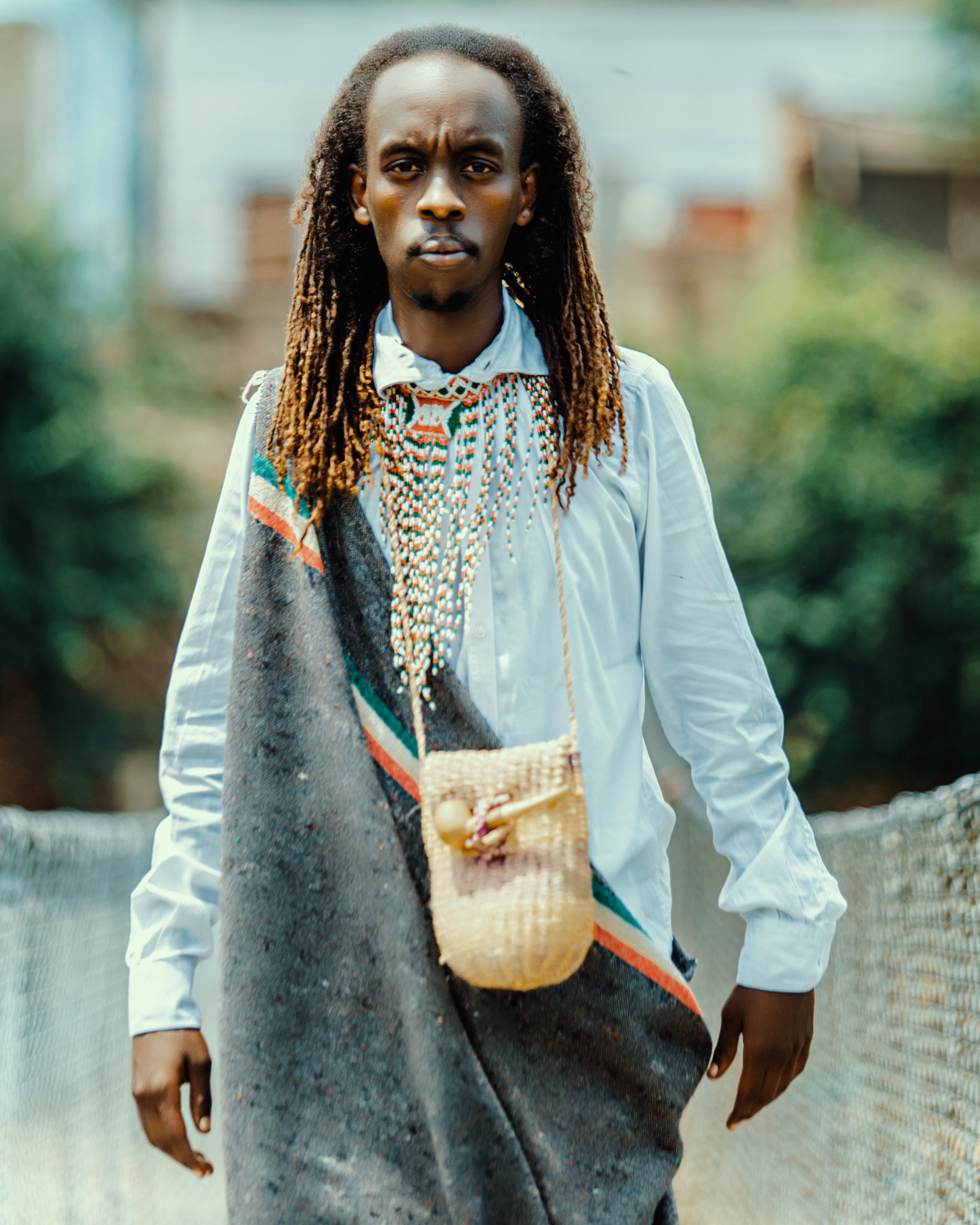 Portrait of a man in traditional African clothing walking on a bridge outdoors.