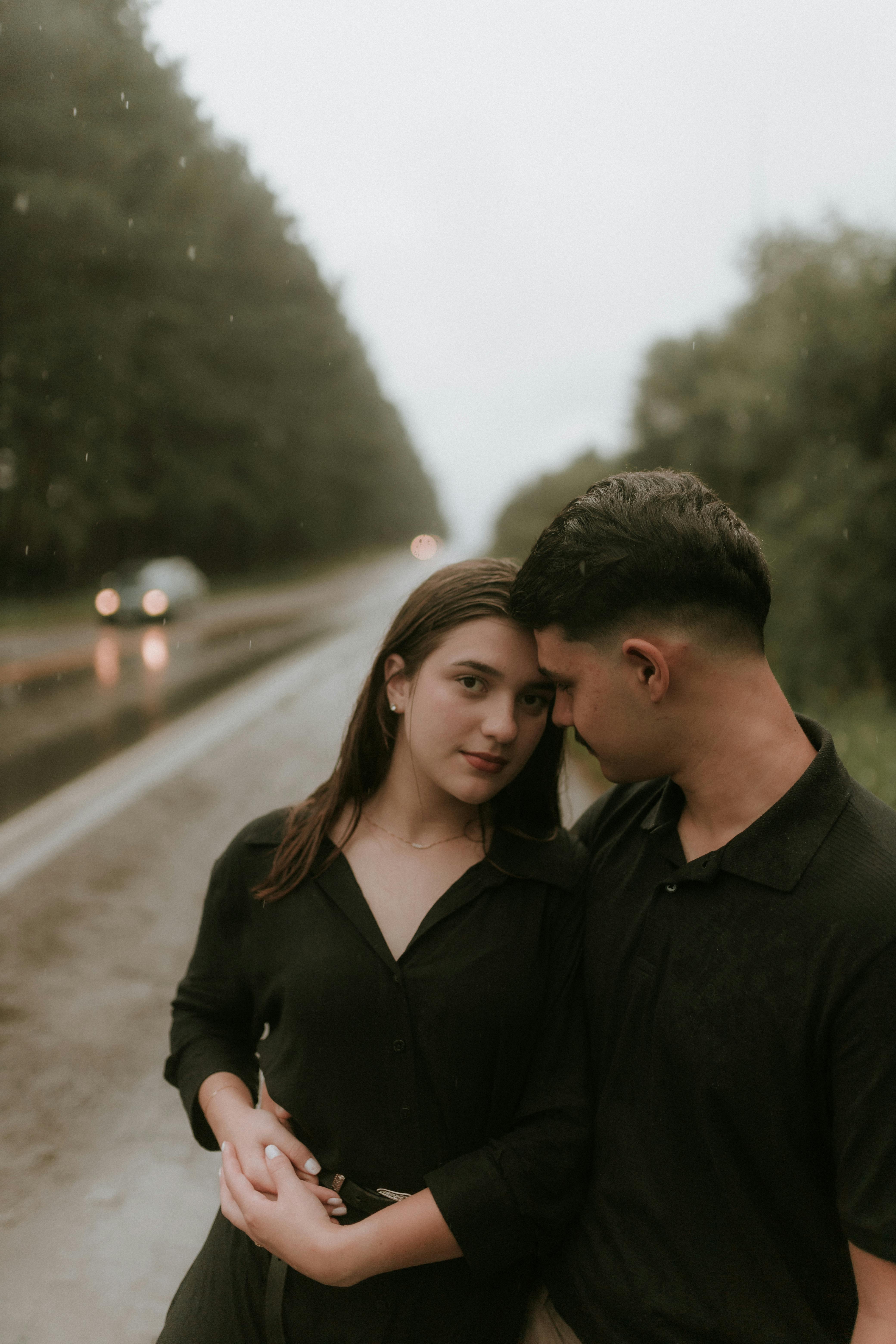 Romantic couple embracing softly as rain falls outside, intimate and serene in dim light
