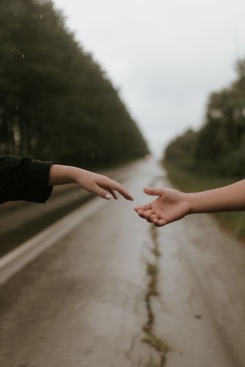 Free Two hands reaching towards each other on a rainy road. Symbol of connection. Stock Photo