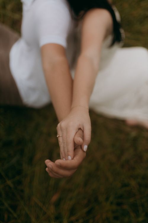Free A close-up of a couple holding hands on grass, symbolizing love and connection. Stock Photo