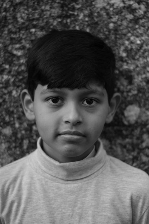 Free Black and white portrait of a young boy against a textured wall, capturing innocence. Stock Photo