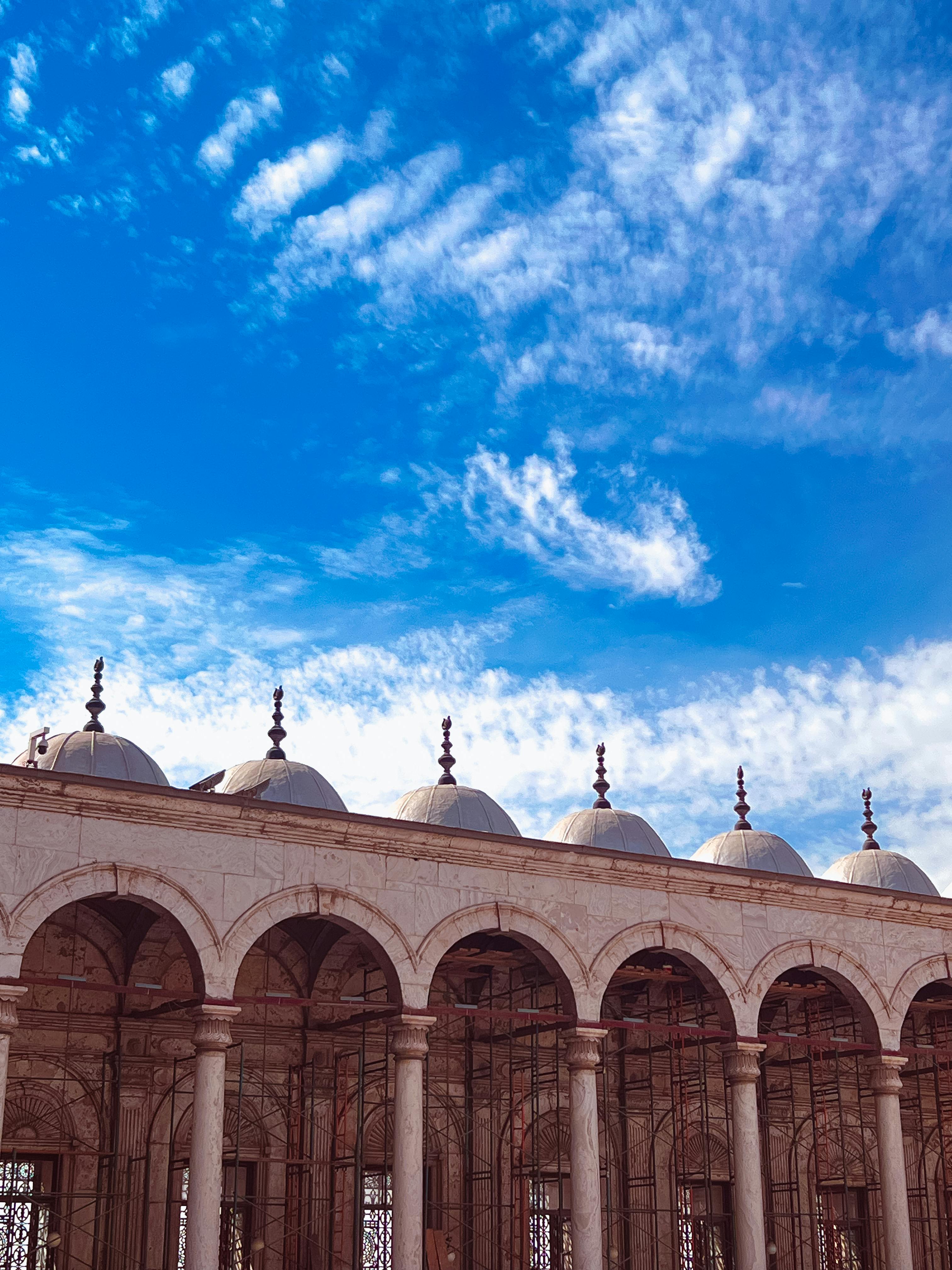 Stunning view of Islamic architecture with domes and arches against a bright blue sky in Cairo, Egypt.