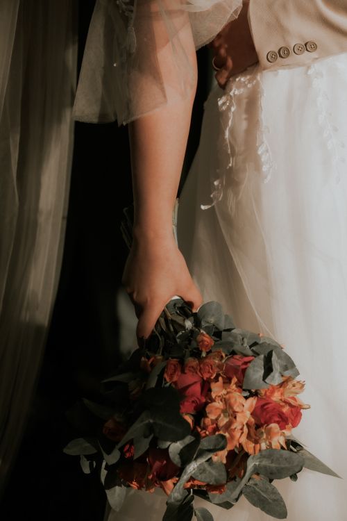Free Bride holding a vibrant bouquet in an elegantly lit wedding scene. Stock Photo