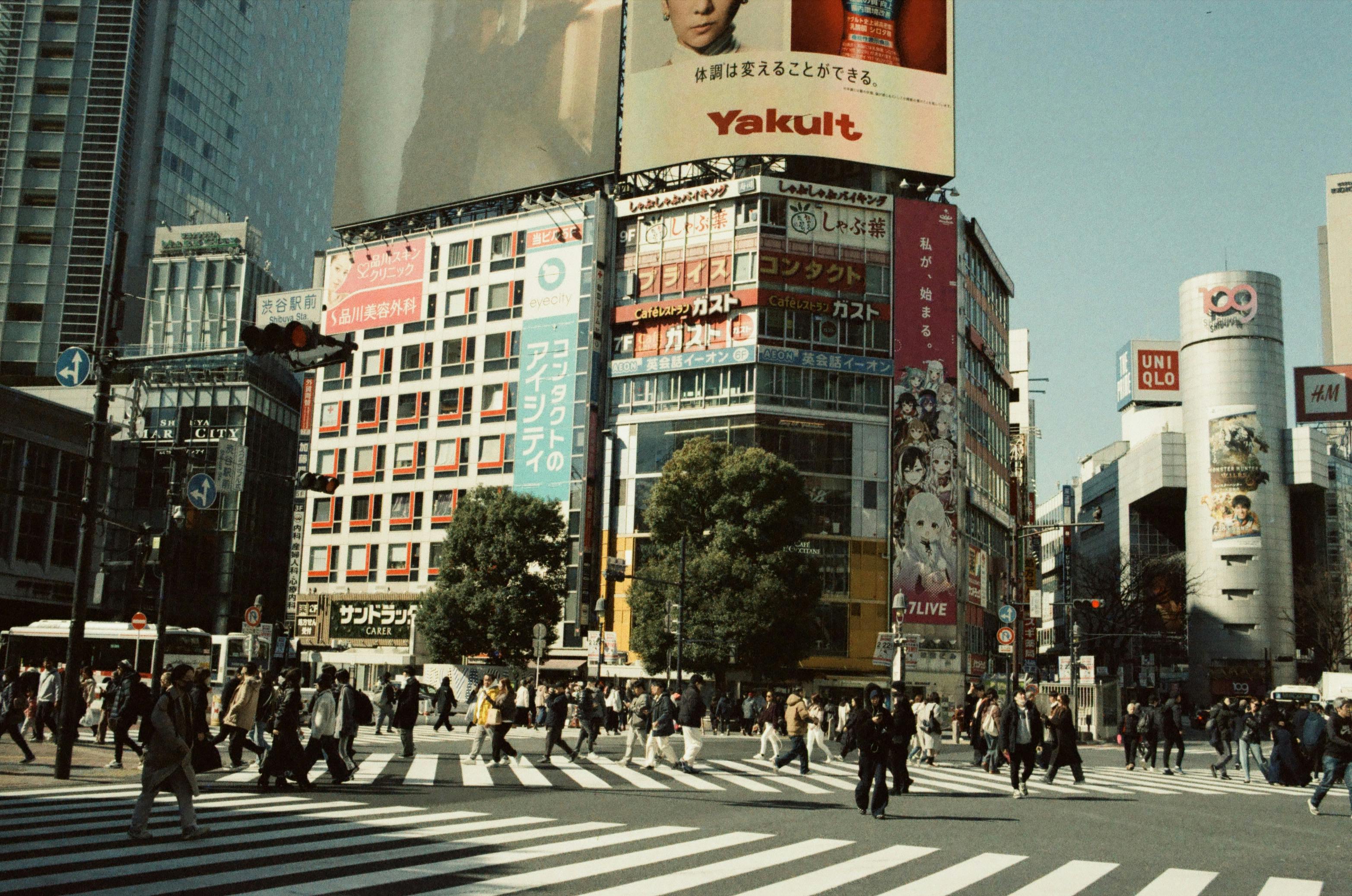 Vibrant street scene of a Tokyo crossing filled with pedestrians and iconic billboards.