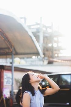 在阳光明媚的城市里，一位年轻女子抬头仰望，背景是建筑