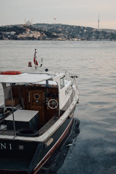 A serene vintage boat on the Bosphorus with Istanbul's skyline at sunset, capturing the moody ambiance.