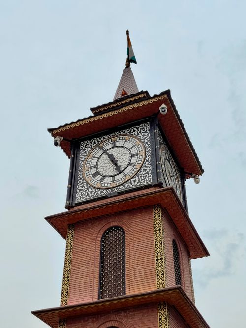 Free Close-up of an intricate clock tower with a flag, highlighting architectural beauty on a clear day. Stock Photo