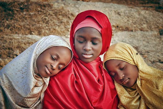 A serene outdoor portrait of three young girls in colorful hijabs, resting peacefully.