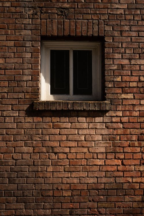 Free A historic brick facade with a wooden window frame showcasing vintage architectural elements, ideal for urban texture themes. Stock Photo