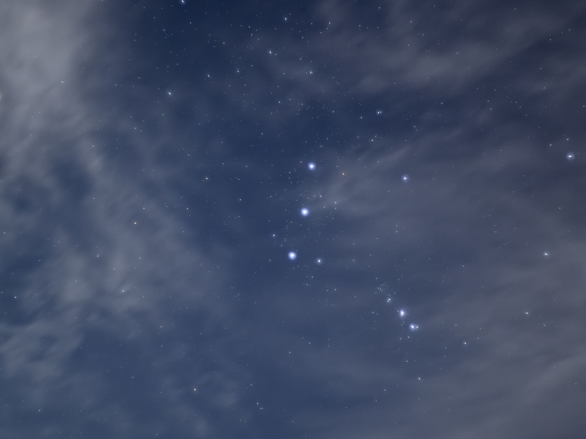 Stunning view of the Orion constellation surrounded by clouds and stars in the night sky.