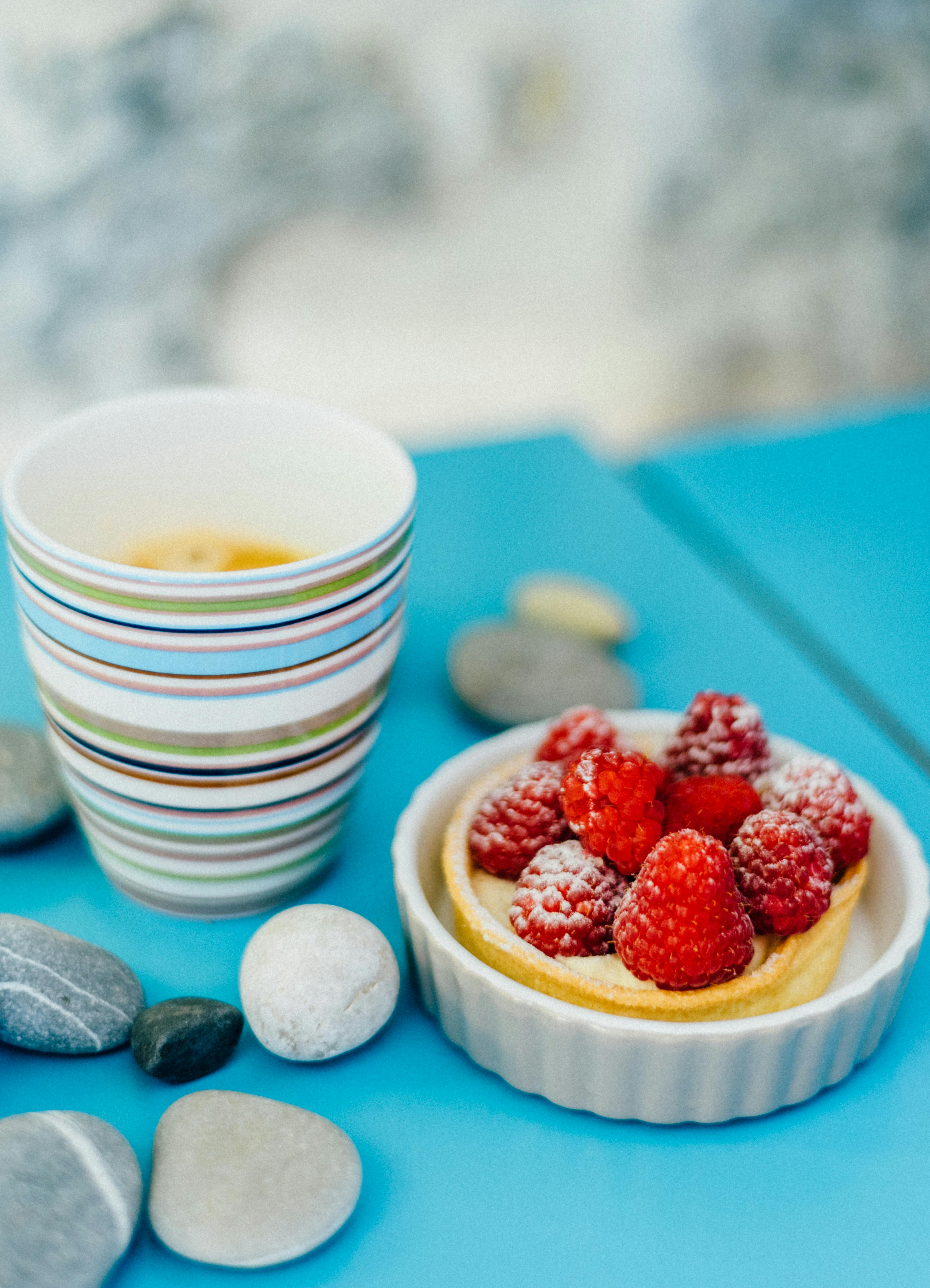 Delicious raspberry tart with a cup of coffee set on a vibrant blue table, ideal for a cozy breakfast setting.