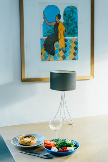 A serene dining setup with a salad and tart, and art piece in a modern interior.