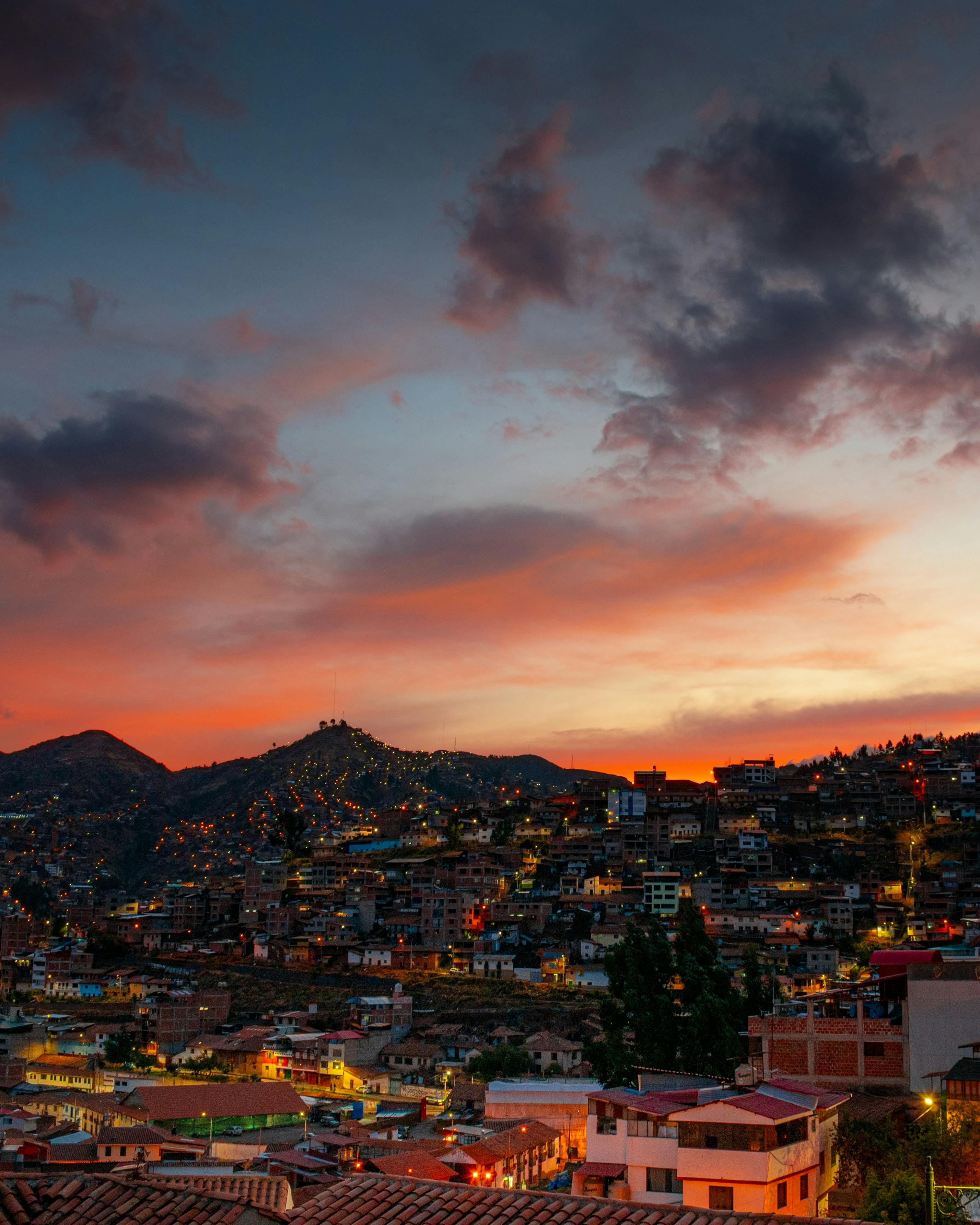 Beautiful sunset view over Cusco, Peru, showcasing vibrant city lights and mountainous landscape.