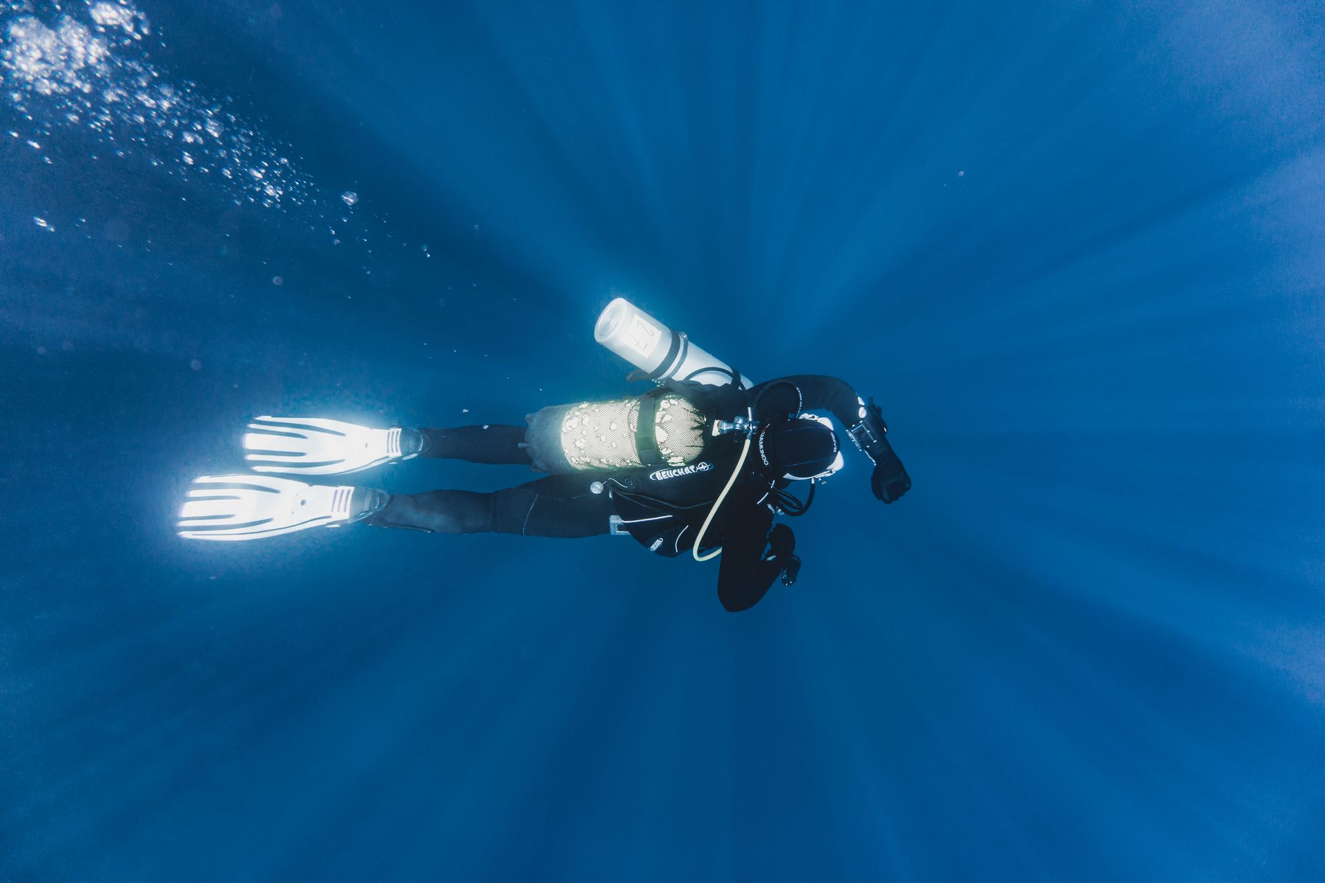A diver in full gear explores the deep blue ocean, showcasing underwater adventure.