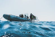 在阳光明媚的日子里，配备水肺的潜水员从充气船上做好了海洋潜水的准备