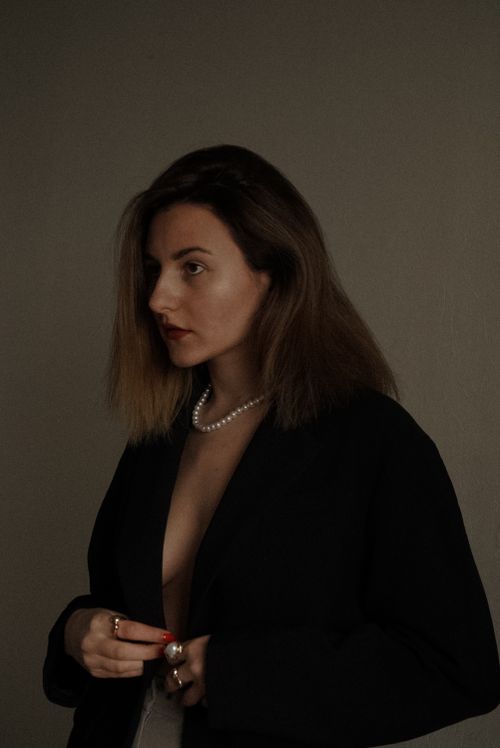 Free Profile portrait of a woman in dark attire and pearl necklace, conveying elegance. Stock Photo