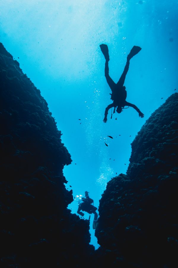Divers descending between reef walls