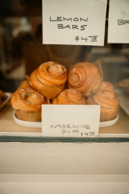 Morning buns in a bakery window with handwritten price cards — photo by James Collington on Pexels