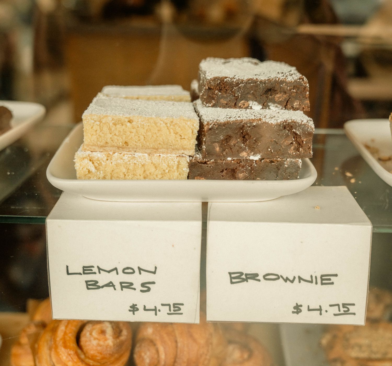 Delicious display of lemon bars and brownies in a bakery with price tags.