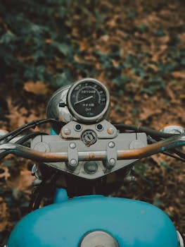 Retro motorcycle handlebar and speedometer, showcasing classic style in an outdoor setting.