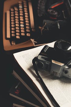 复古场景中，一本打开的书上摆放着一台老式相机和一台打字机