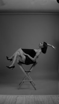 Black and white studio portrait of woman reclining on chair, exuding elegance.