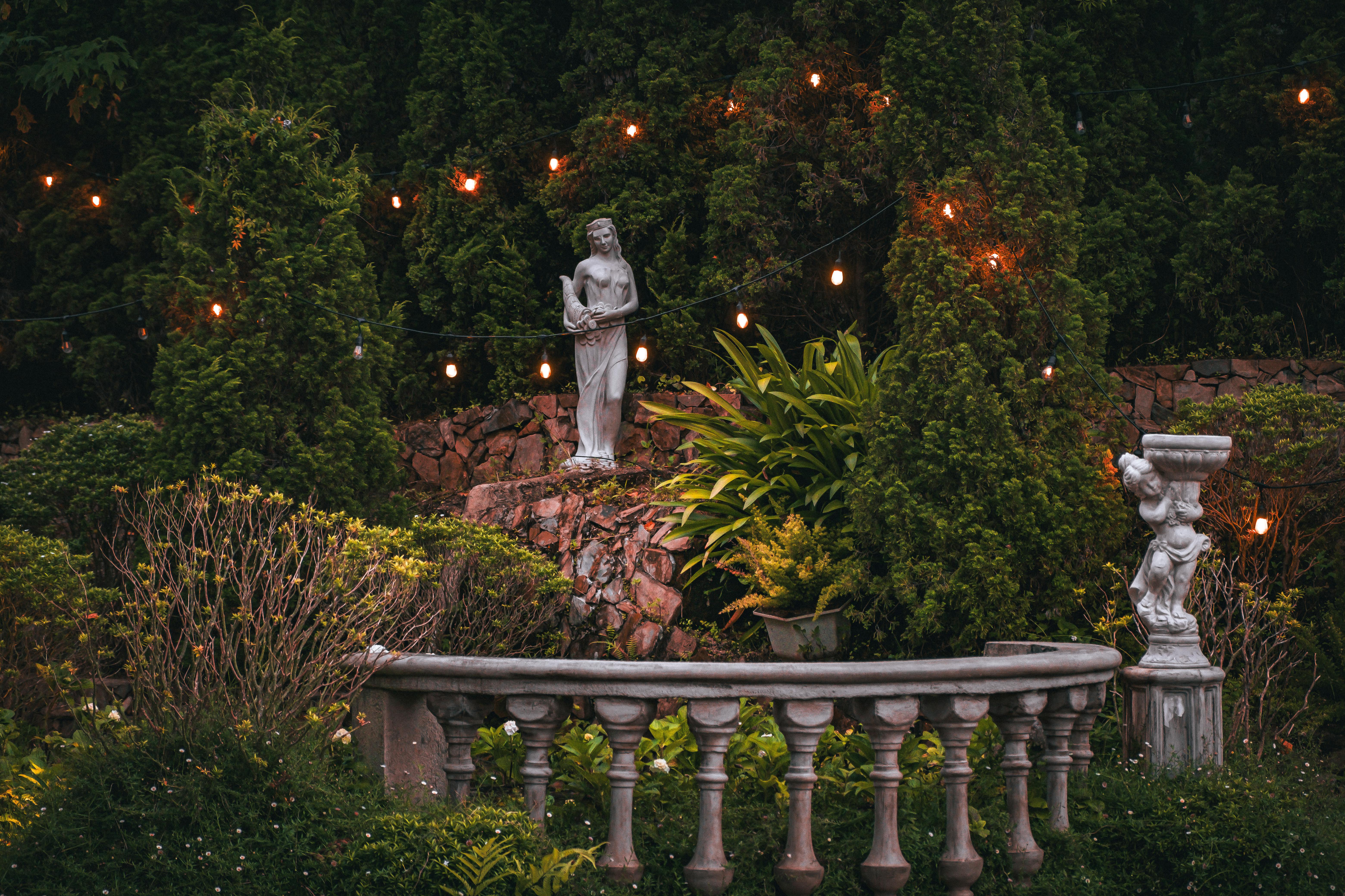 Tranquil Garden with Statues and String Lights · Free Stock Photo