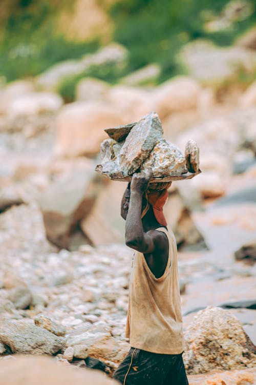 Worker Carries Rocks in Quarry Setting Outdoors · Free Stock Photo