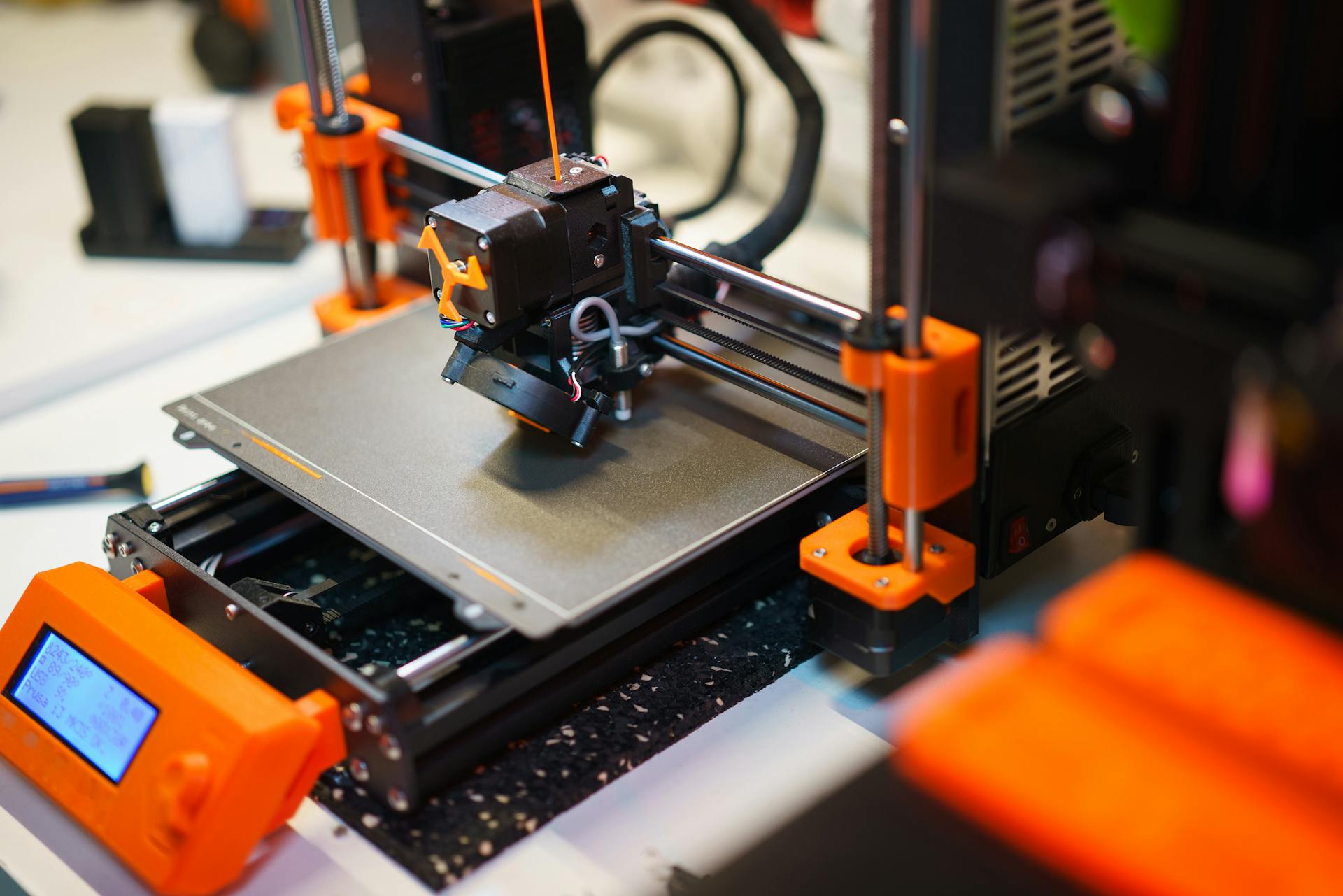 Detailed view of a 3D printer creating an object with orange components.