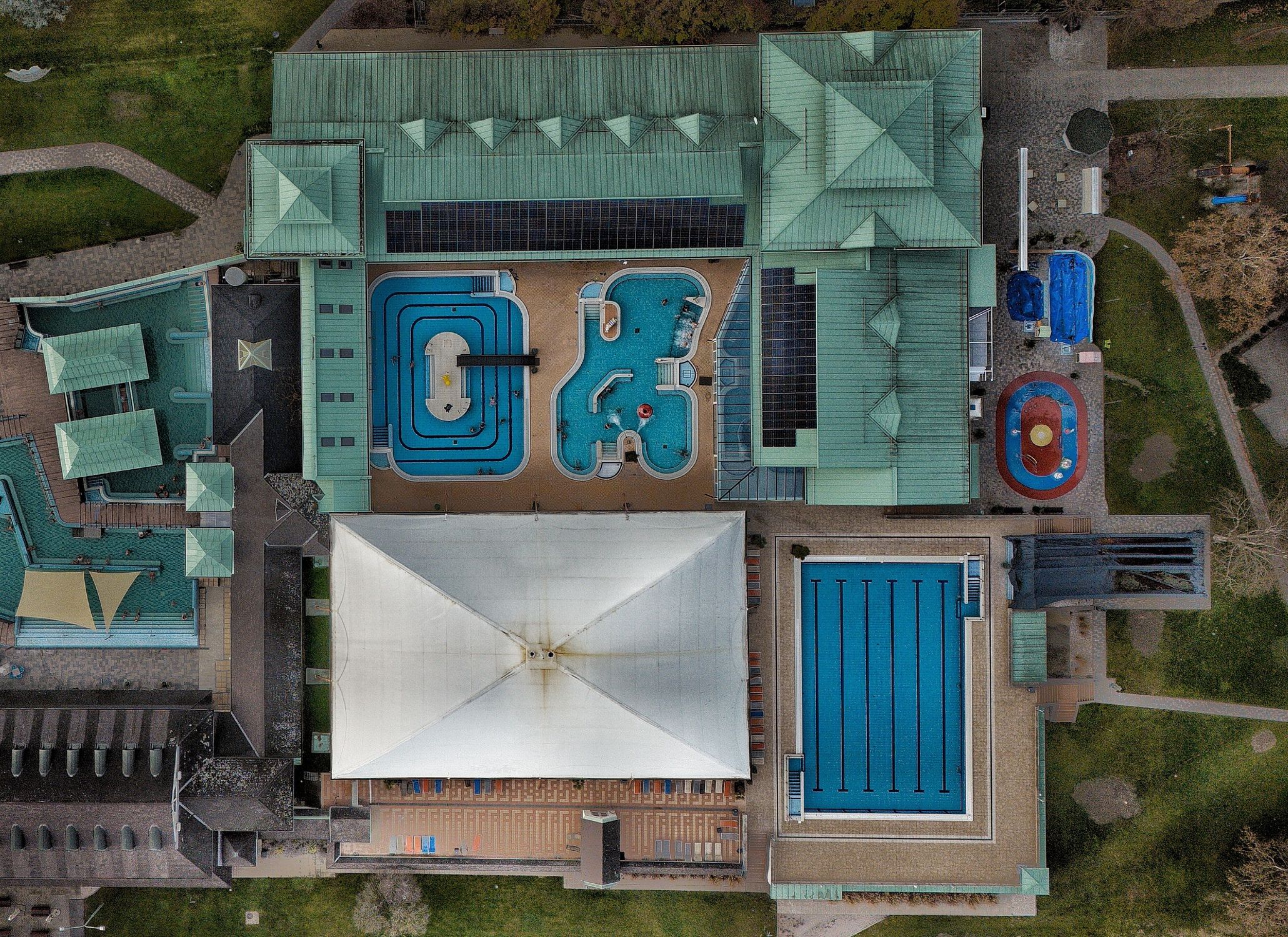 A modern aquatic center featuring multiple swimming pools and green rooftop.