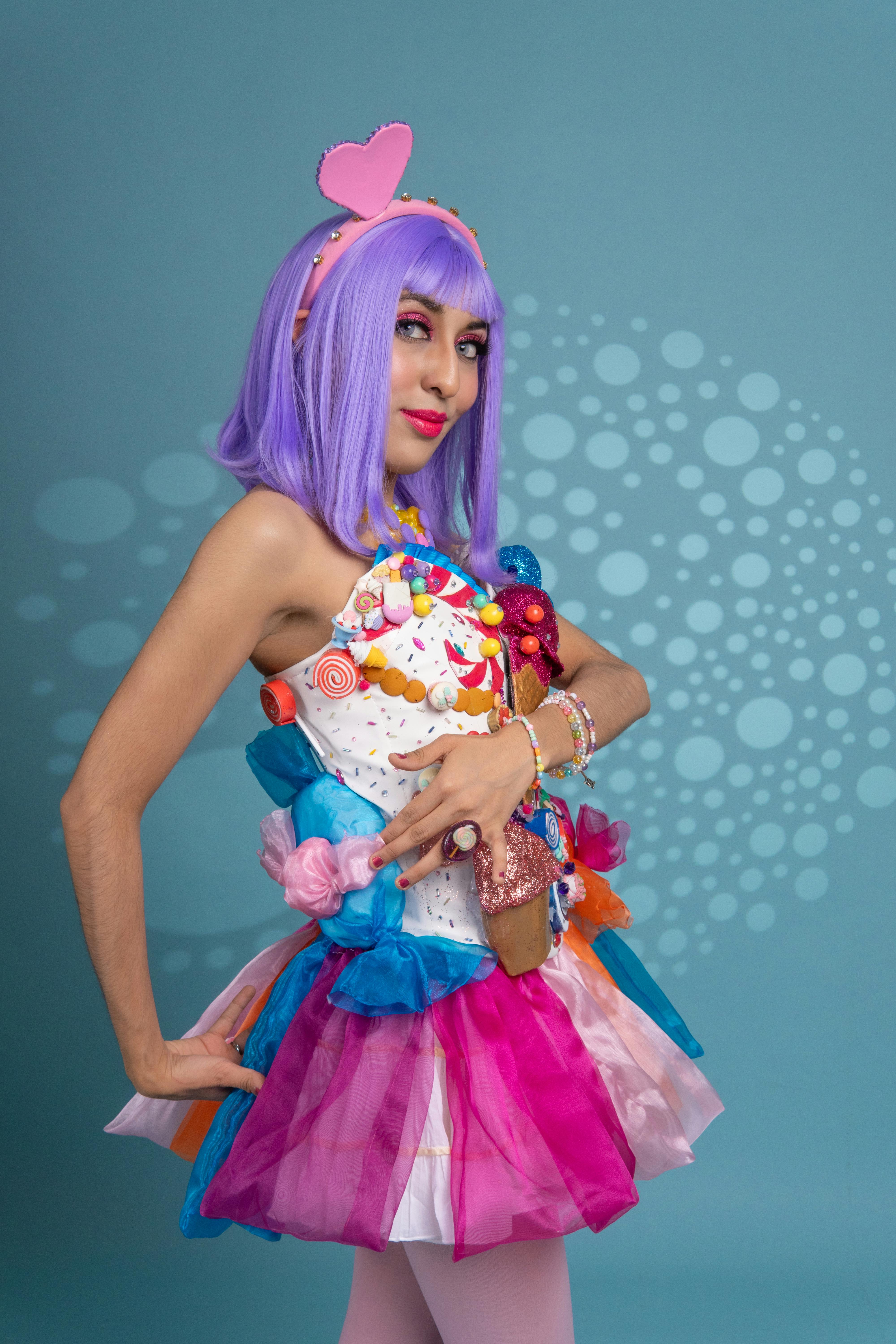 ingyenes Élénk cosplay egy színes öltözékben, lila hajú nővel, kék háttér előtt. Stockfotó