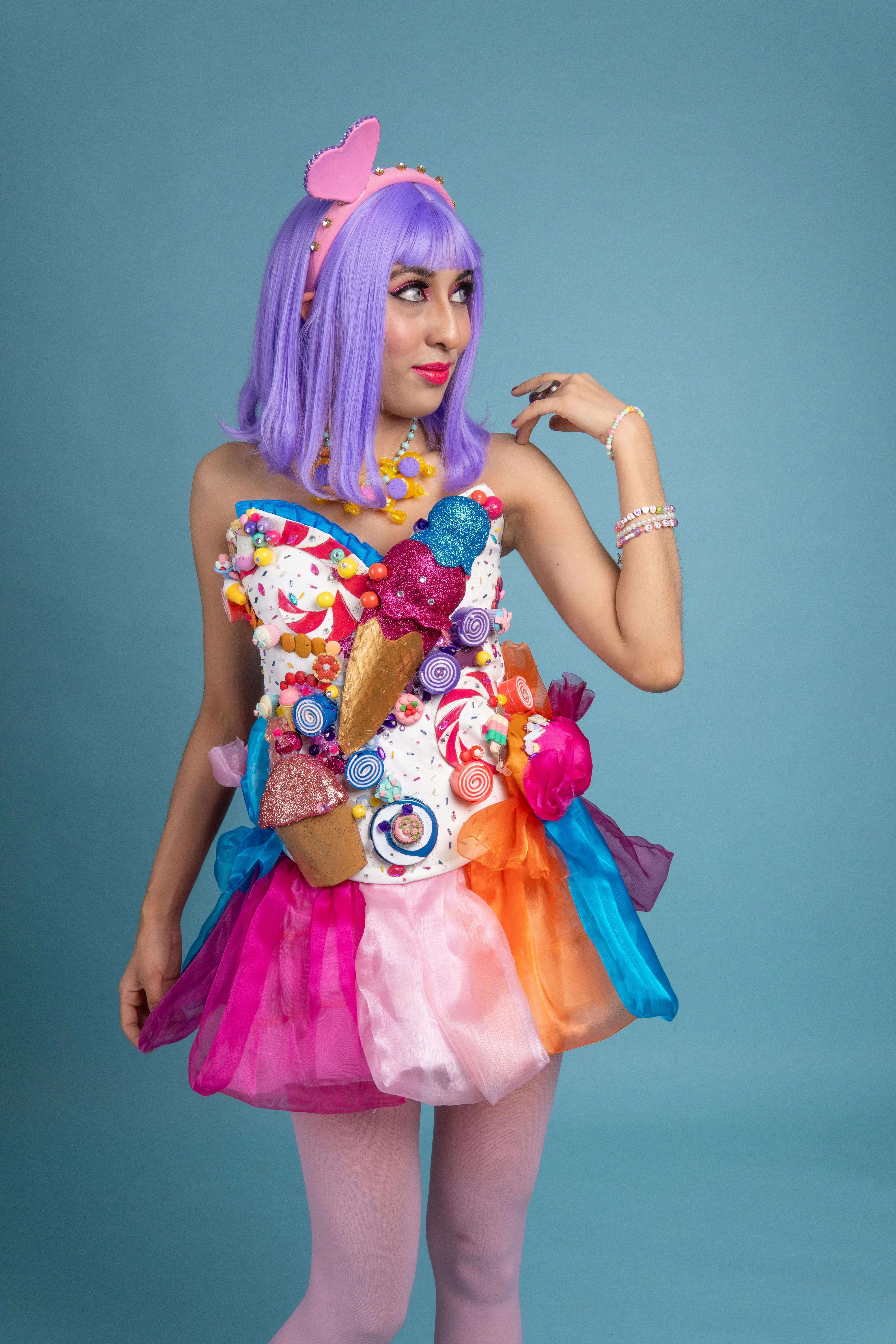 ingyenes Színes cosplay egy fiatal nővel, cukorka témájú jelmezben, lila hajjal, kék háttérrel. Stockfotó