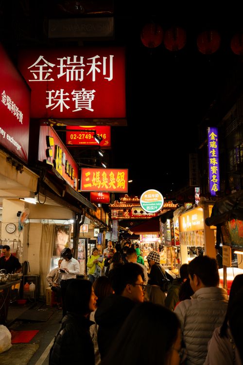 Free Vibrant street scene at an Asian night market with colorful neon signs and busy crowd. Stock Photo