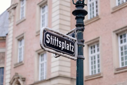 Close-up of Stiftsplatz street sign against historic architecture in Düsseldorf, Germany.
