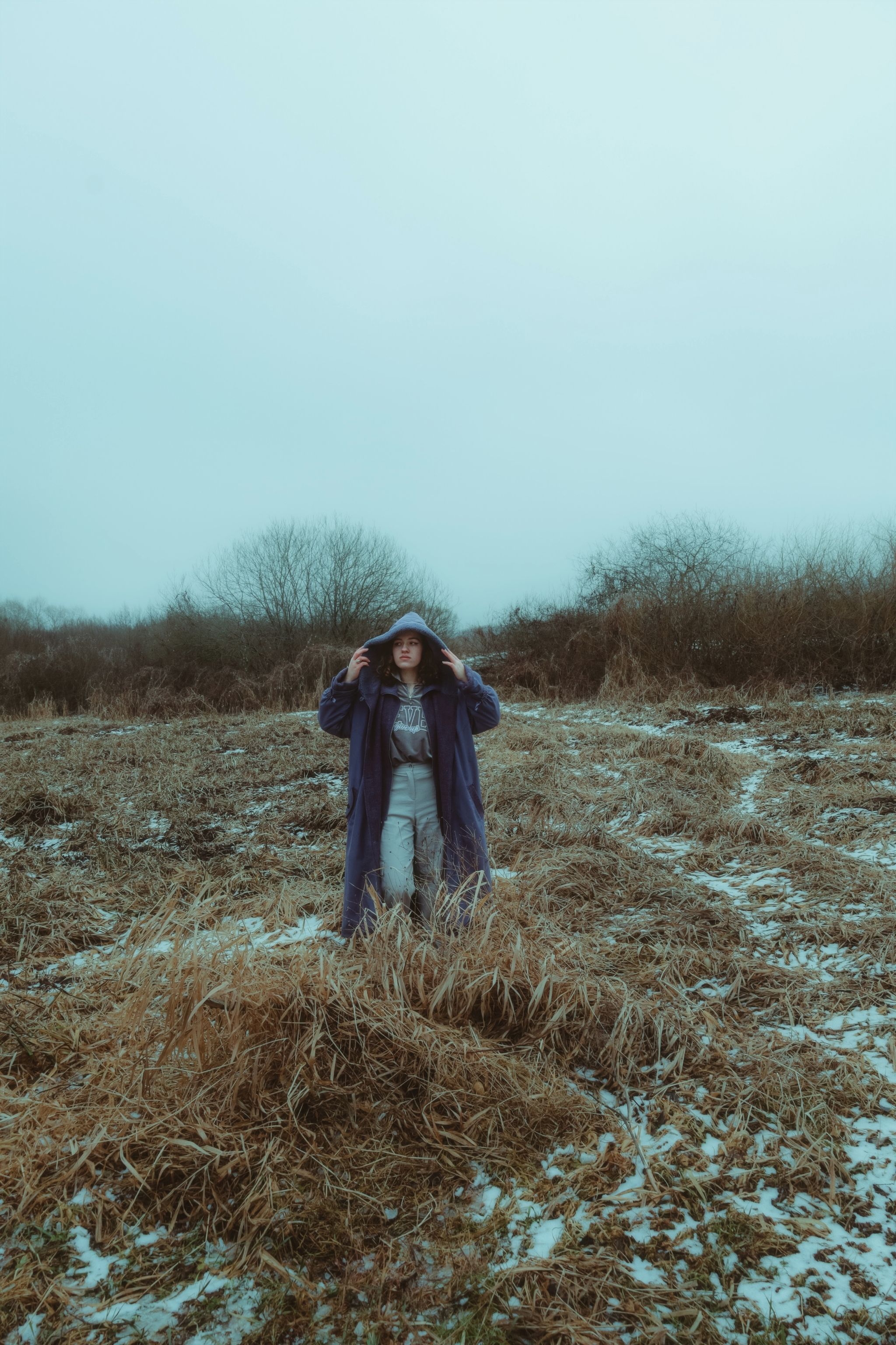 Woman Standing in Winter Field with Sparse Snow · Free Stock Photo