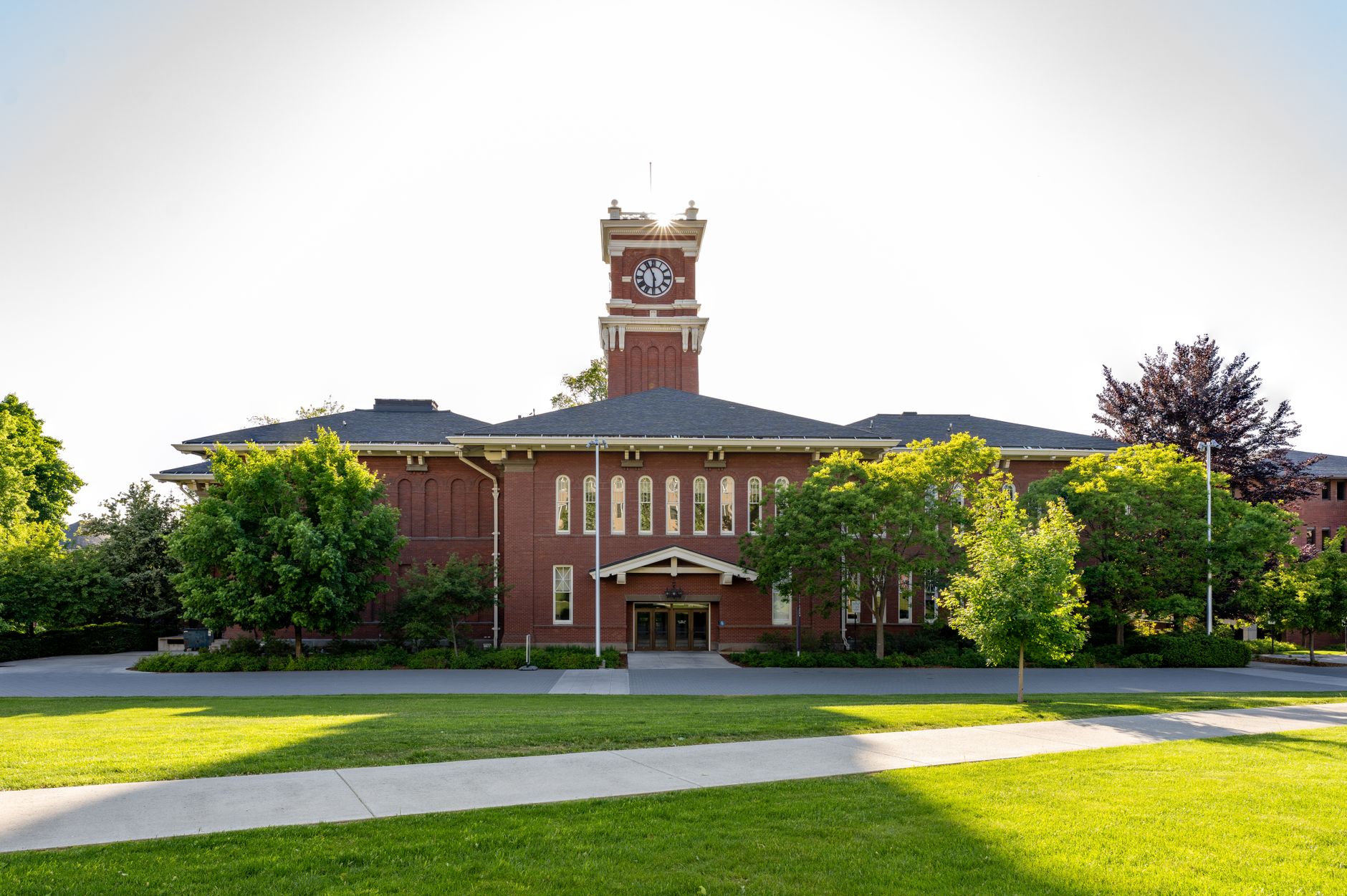 Historic clock tower at WSU Pullman campus surrounded by green lawns and trees.