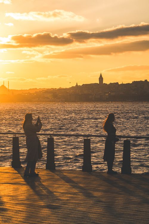 Free Two people silhouetted against the Bosphorus at sunset, capturing the beauty of Istanbul. Stock Photo