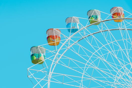 Bright and colorful Ferris wheel with vibrant cabins set against a clear blue sky.